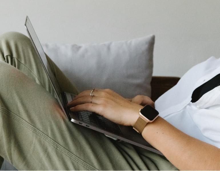 Figure reclining on sofa with laptop